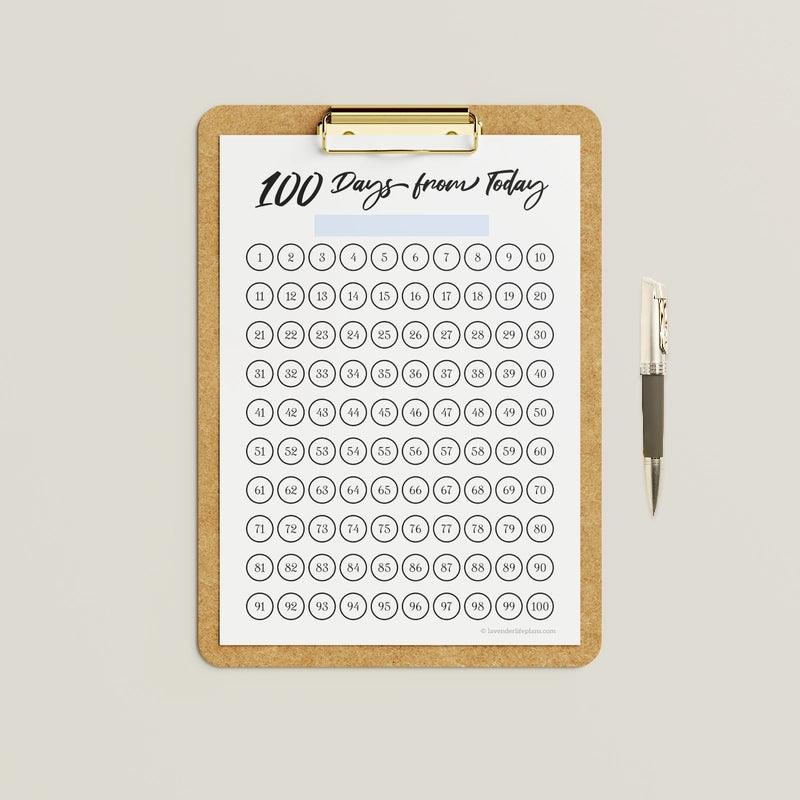 Mockup showing an example of use for the black and white version of the '100 Days from Today' printable 100-day challenge calendar, which can be colored in by hand.